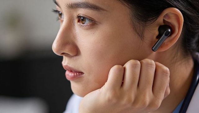 Female clinician listening with wireless earbud and stethoscope close-up