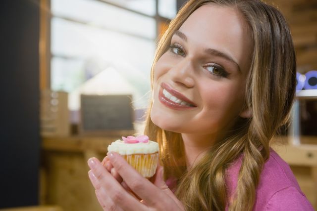 Portrait of beautiful woman holding cupcake in cafÃ©