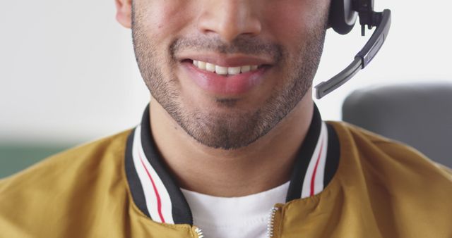 Close-up of a cheerful customer service representative wearing a headset. His friendly demeanor suggests a positive interaction in an office setting.