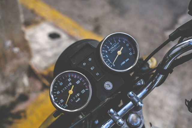 Vintage motorcycle handlebar featuring a close-up of speedometer and tachometer gauges. Ideal for use in articles about vintage bikes, motorcycle maintenance, and classic automotive design.