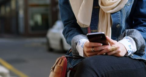 Young Woman in Hijab Using Smartphone in Urban Setting