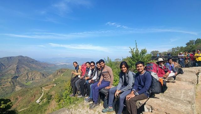 Hiking group posing on mountain ridge overlooking valley with backpacks and panoramic view