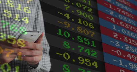 Holding Smartphone Monitoring Live Market Ticker, Stocks and Trading Data Dashboard