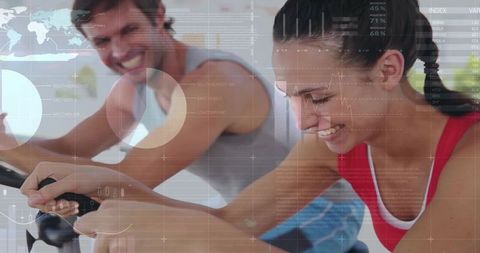 Energetic Couple Enjoying Workout on Exercise Bikes in Bright Studio