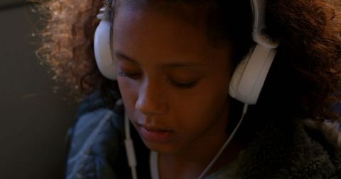 Young girl wearing headphones enjoying music on bus journey