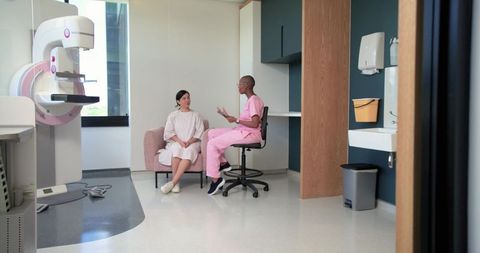 Female technologist consulting patient before mammogram in modern radiology clinic