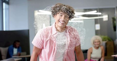 Smiling man wearing pink striped shirt standing in modern coworking lounge with digital swirl