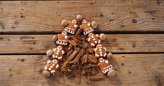 Gingerbread cookies decorated with white icing are arranged on a rustic wooden surface, surrounded by cinnamon sticks, evoking a cozy, festive atmosphere. These treats are often associated with holidays and celebrations, adding a sweet touch to seasonal gatherings.