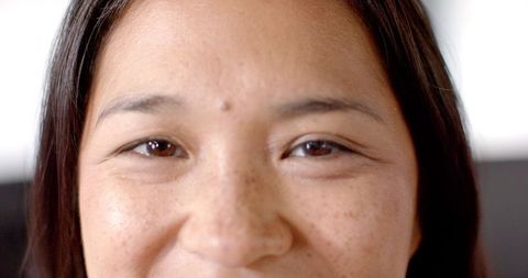 Close-up of smiling woman highlighting natural beauty and freckles