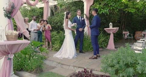 Bride and groom exchanging vows in outdoor ceremony among family