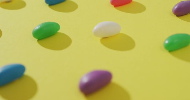 Image of close up of rows of multi coloured sweets over yellow background. fusion food and sweets concept.
