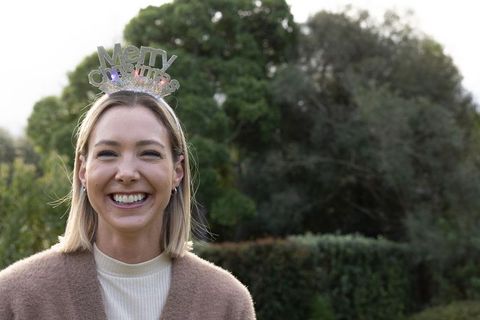 Smiling woman wearing merry christmas headband outdoors in garden festive casual portrait