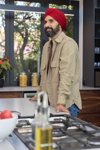Indian man in modern kitchen with red turban and cooking elements