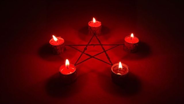 Tealight candles in pentagram shape on dark tabletop