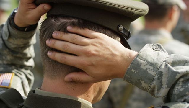 Soldier adjusting cap during military formation with u.s. Flag patch