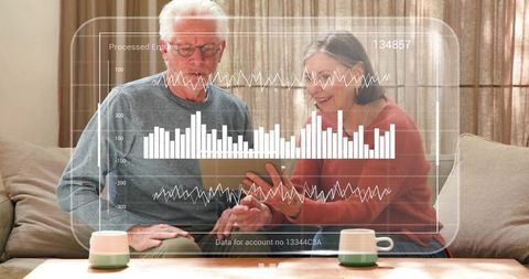 Senior couple exploring interactive digital analytics on tablet in cozy home living room
