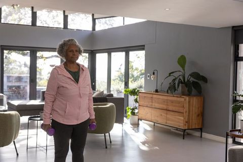 Senior Woman Exercising in Spacious Modern Living Room with Dumbbells