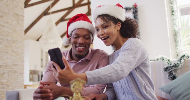Happy african american couple with santa hats having image call. Spending quality time at christmas together concept.