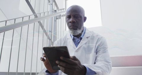 Senior scientist using tablet on staircase landing in minimalist laboratory environment