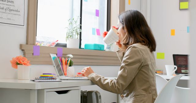 Businesswoman Sipping Coffee at Modern Office Desk with Laptop - Download Free Stock Images Pikwizard.com