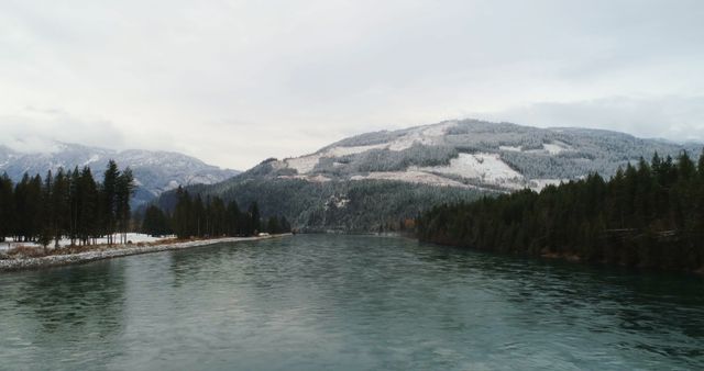 Serene winter lake with snow-covered mountain in the background. Ideal for promoting outdoor travel destinations, winter holiday packages, or nature conservation campaigns.