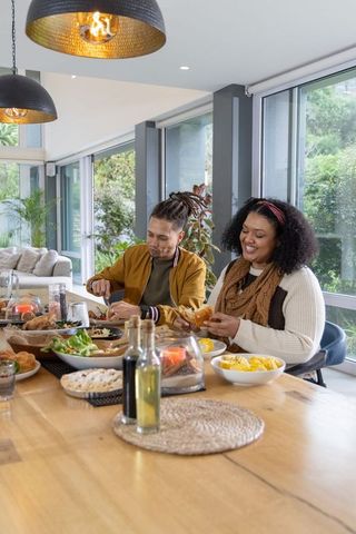 Couple enjoying relaxed home-cooked meal in bright open-plan dining under pendant lights