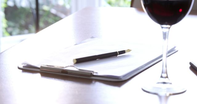 Close-up of Clipboard with Pen Next to Glass of Red Wine - Download Free Stock Images Pikwizard.com