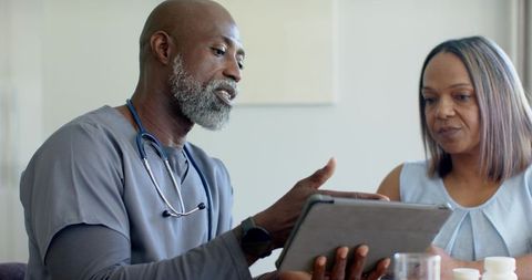 African american clinician consulting female patient using tablet to review medication plan