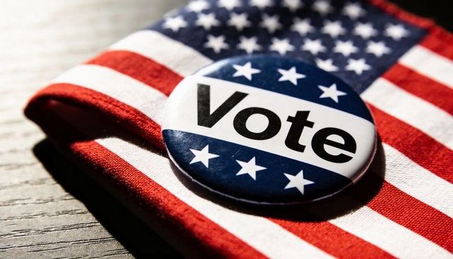 Closeup vote button on folded american flag for voter awareness and election campaigns