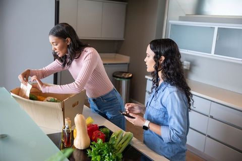 Two Women Unpacking Fresh Vegetables in Modern Kitchen