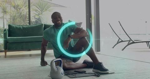 Smiling man resting after kettlebell workout in modern living room with glass patio doors