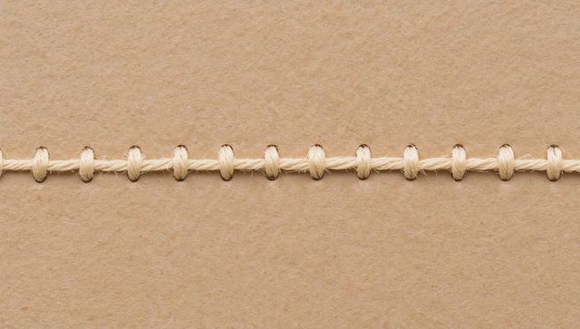 Beige twine running across kraft paper stitching seam for packaging crafting and stationery