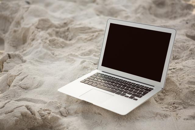 Laptop kept on sand at beach