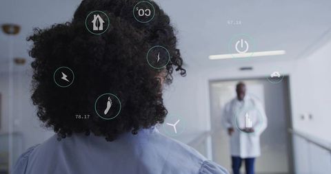 Patient in hospital gown viewing approaching doctor with holographic medical icons