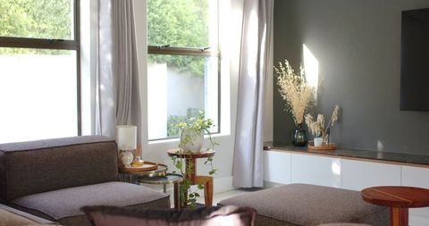 Modern neutral living room with sectional chaise, sunlit ottoman and minimalist console