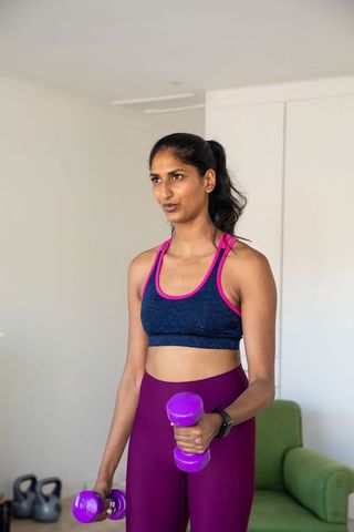 Indian woman exercising with dumbbells in home gym setting