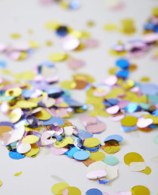 Photo displays a close-up of brightly colored confetti spread on a white surface, creating a festive and joyful scene. It can be used for conveying celebration themes, decorations for events, party invitations, and festive designs. Ideal for new year, weddings, or birthdays.