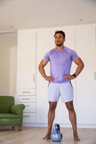 Asian Man Standing with Kettlebell in Home Workout Space
