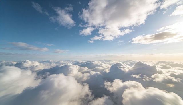 Sunlit cumulus clouds rolling across vast blue sky with golden horizon, wide aerial sweep