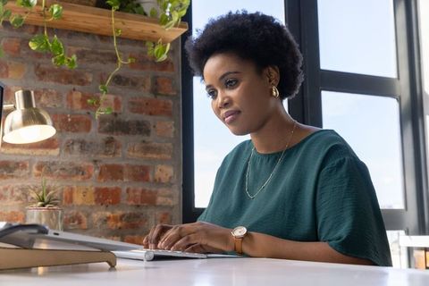 Professional Woman Typing at Home Office Desk with Greenery