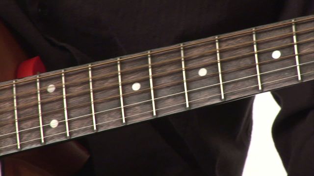 An artistic shot of a guitar fretboard showing fingers carefully positioned for playing chords. This portrays themes of music education, musicianship, and artistic dedication. Ideal for use in promotional materials for guitar lessons, music courses, and events. Suitable for websites and print showcasing instruments or focusing on learning music.