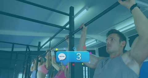 Fitness class performing synchronized pull-ups in gym