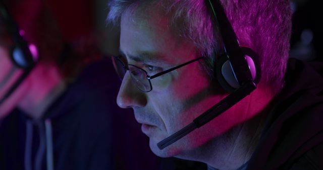 Middle-aged Man with Headset in Dark Office Lit by Neon Lights - Download Free Stock Images Pikwizard.com