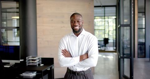 Confident Businessman Standing with Arms Crossed in Modern Office