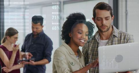 Diverse team collaborating on laptop with digital analytics overlays and business charts