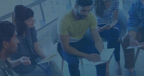 Team Collaborating Around Notebook in Bright Office Space Brainstorming Ideas and Taking Notes