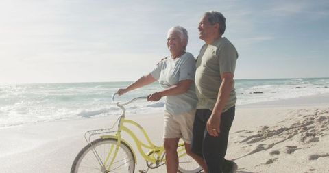 Senior Couple Enjoying Beach Walk with Bicycle at Sunset