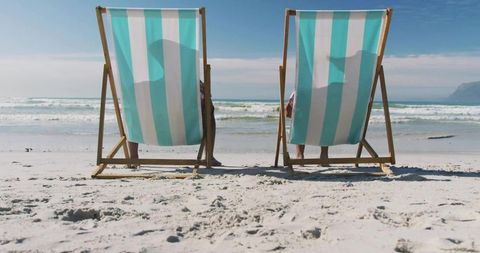 Senior Couple Relaxing in Striped Chairs on Sunny Beach