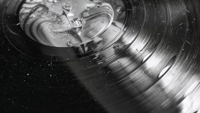 Macro vinyl record grooves with stylus contacting marbled label, dust and texture close-up