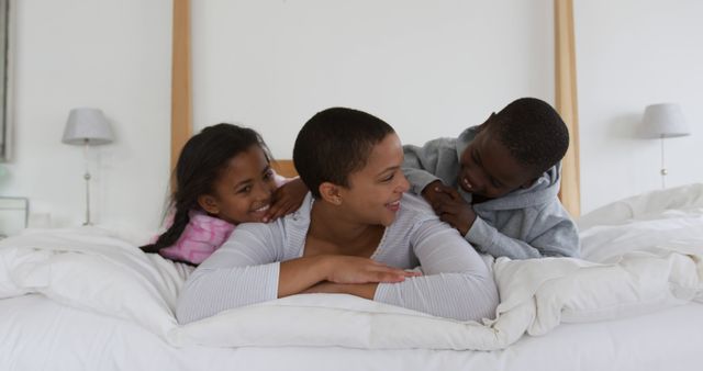 Mother with Children Laughing on Bed in Bright Room - Download Free Stock Images Pikwizard.com